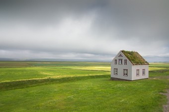 Solitary home in a large green field surrounded by blue skies.